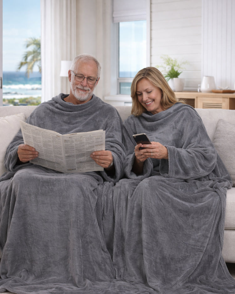 Product image of an older man and women using Slanket Siamese and he is reading the newspaper and she is on her phone