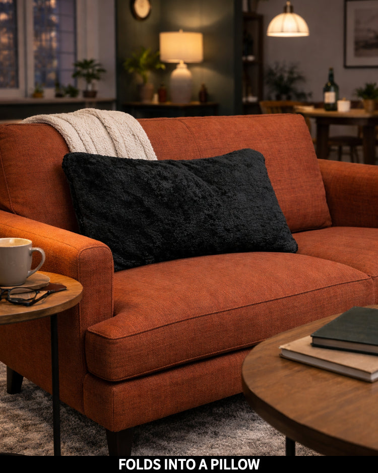 Black Slanket folded into a pillow, shown as a decorative cushion, captioned Folds Into a Pillow