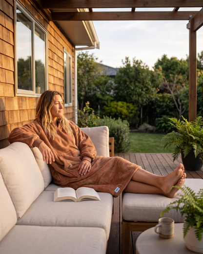 Woman relaxing on a porch sofa in a Mocha Mousse Slanket Long Hoodie