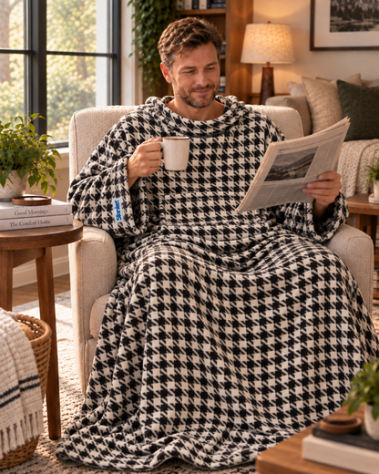 Man holding a mug and a newspaper in an armchair, wearing a Houndstooth Slanket