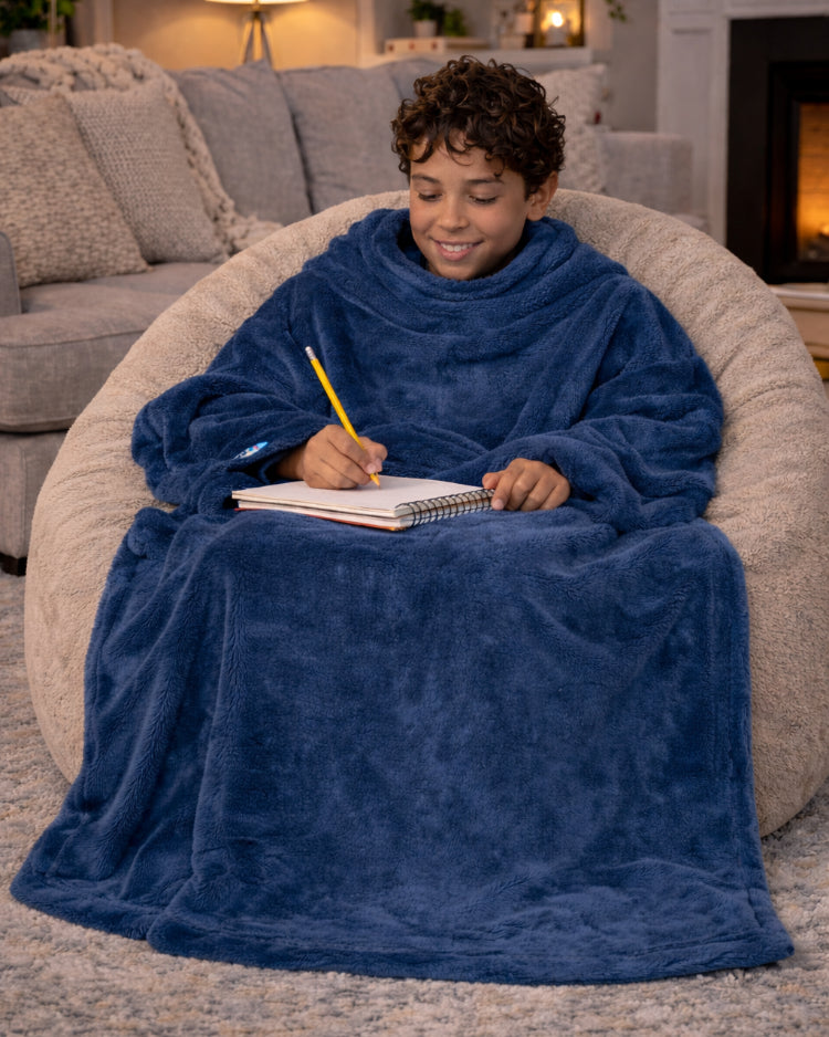 Boy writing in a notebook on a bean bag chair in a blue Slanket Jr.