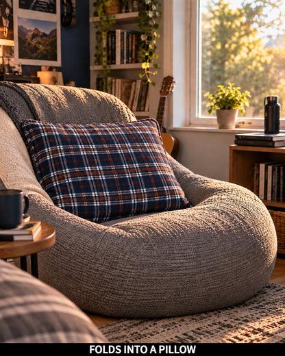 Nor'easter Plaid Slanket Jr. folded into a pillow on a bean bag chair, captioned Folds Into a Pillow