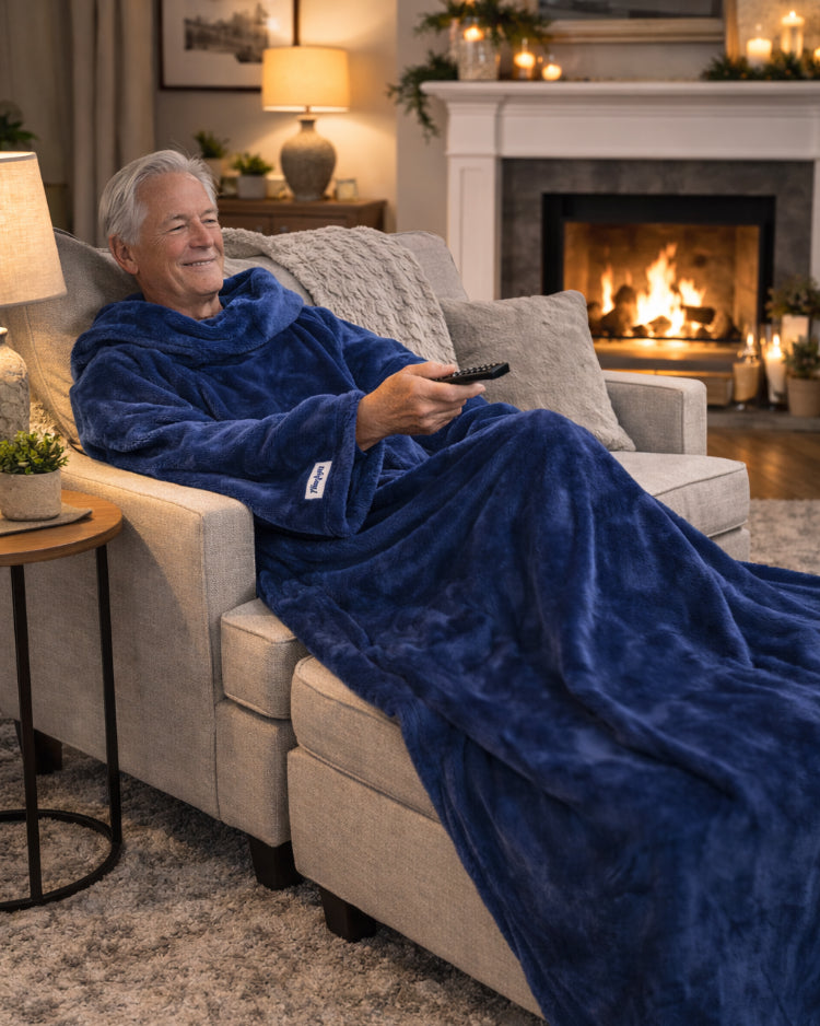 Woman resting by a lit fireplace wearing a Limoges blue Slanket