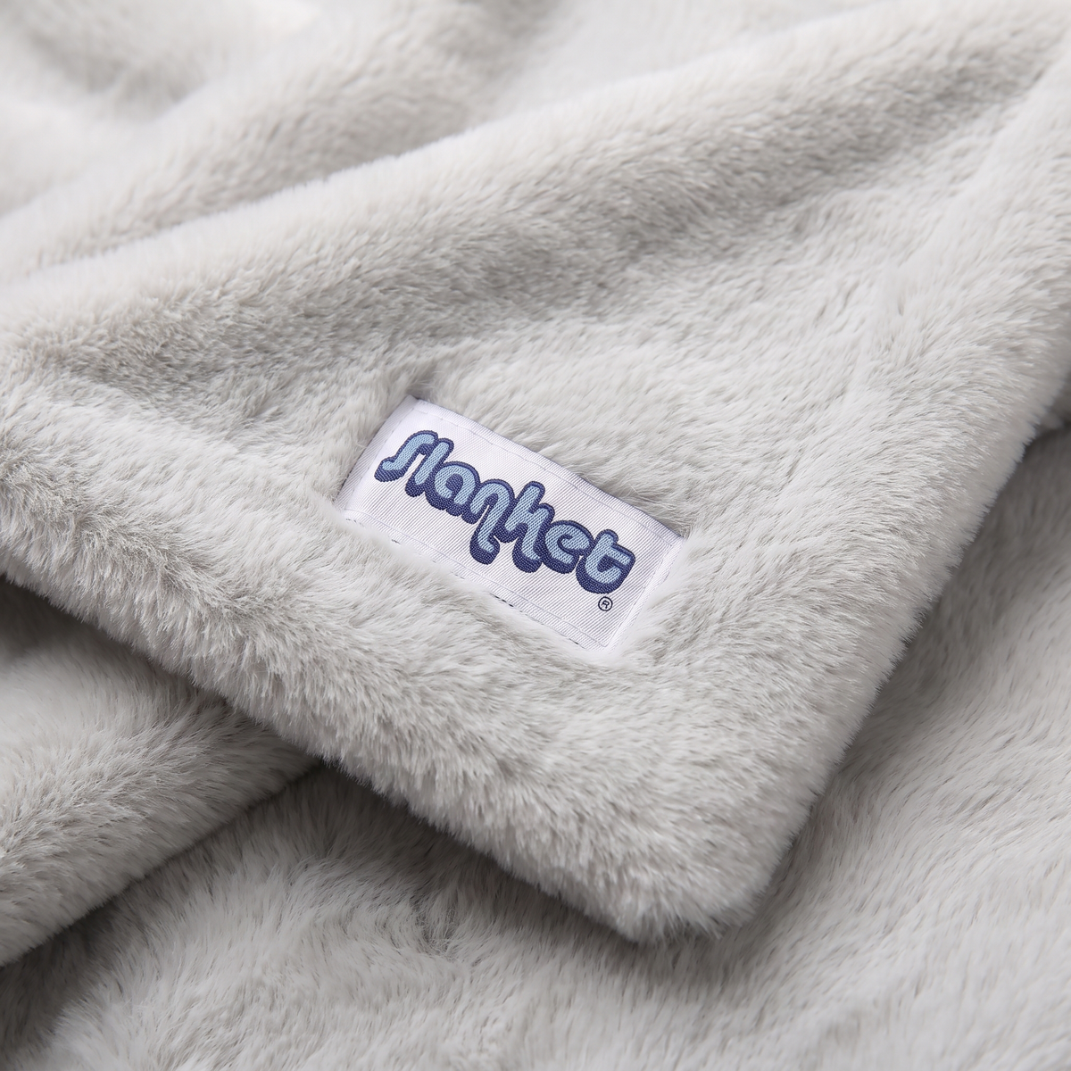 Close-up of Ghost light gray plush with the blue Slanket logo tag