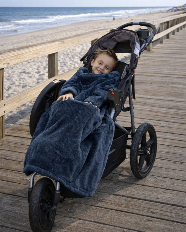 Product image of a little boy using Stroller Slanket while sitting in his stoller by the ocean