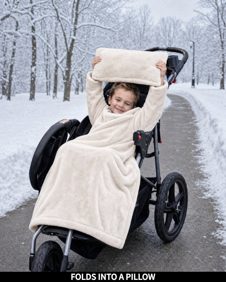 Child in a stroller wrapped in a Cloud Dancer Stroller Slanket, captioned Folds Into a Pillow