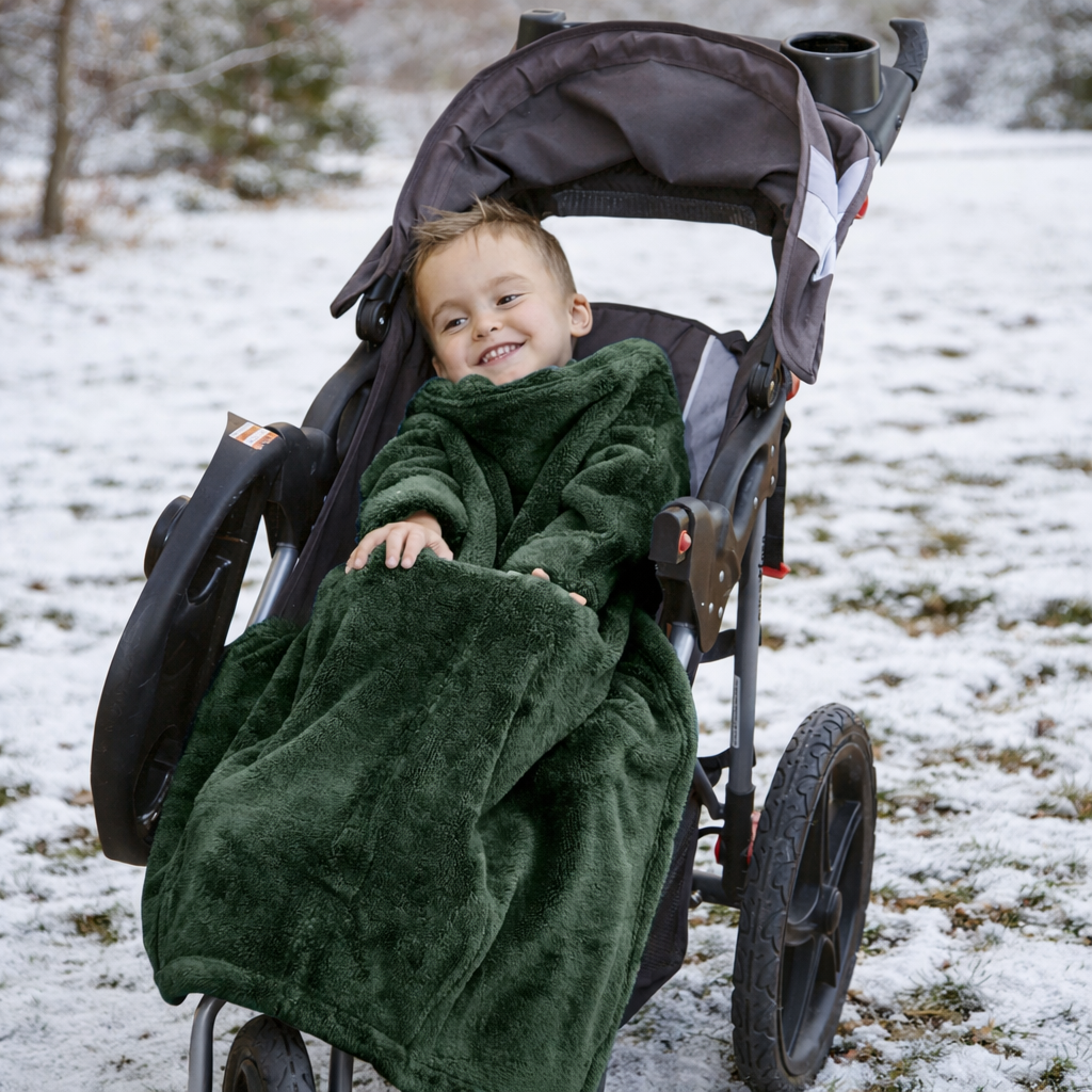 Boy in a stroller using Stroller Slanket looking cozy and warm in a snowy park