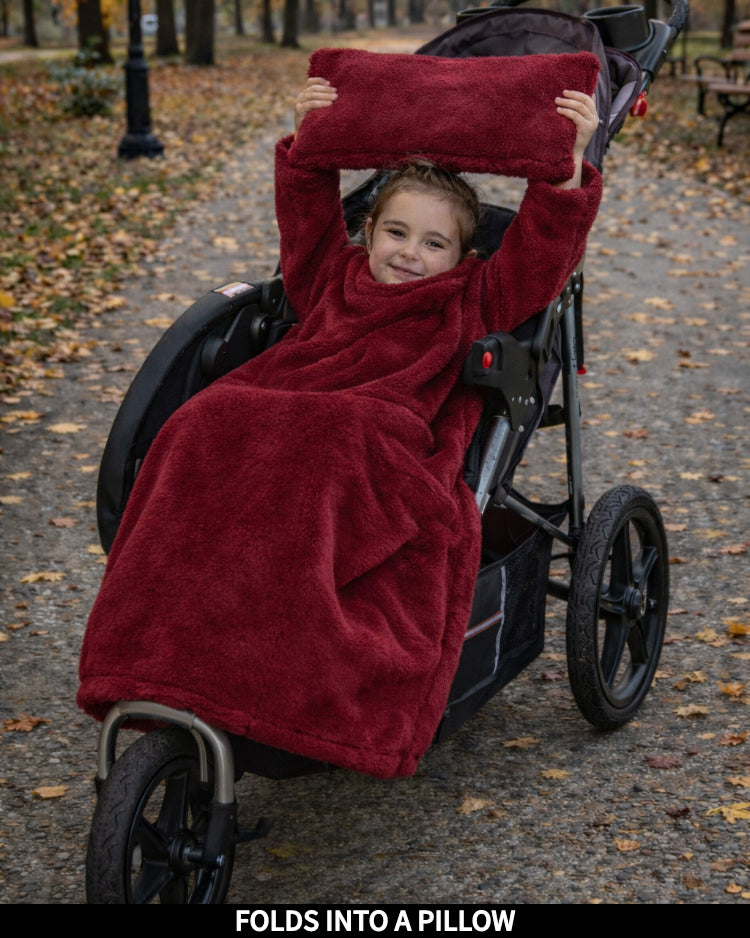 Child in a stroller wrapped in a Ruby Wine Stroller Slanket, captioned Folds Into a Pillow