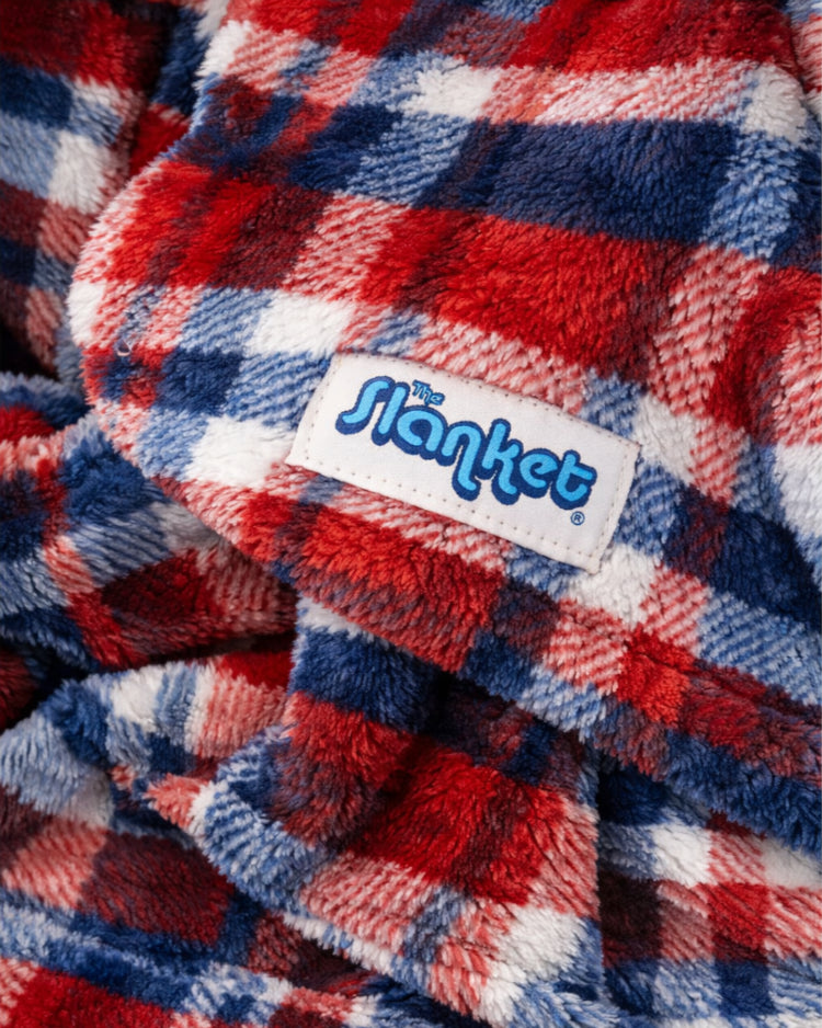 Close-up of a red, blue, and white plaid blanket with 'Slanket' label.